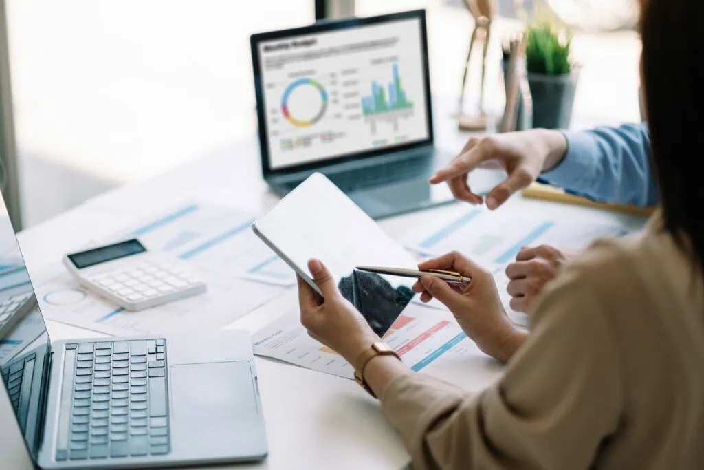 Businesswoman analyzing financial data on tablet and computer screen.