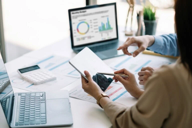 Businesswoman analyzing financial data on tablet and computer screen.